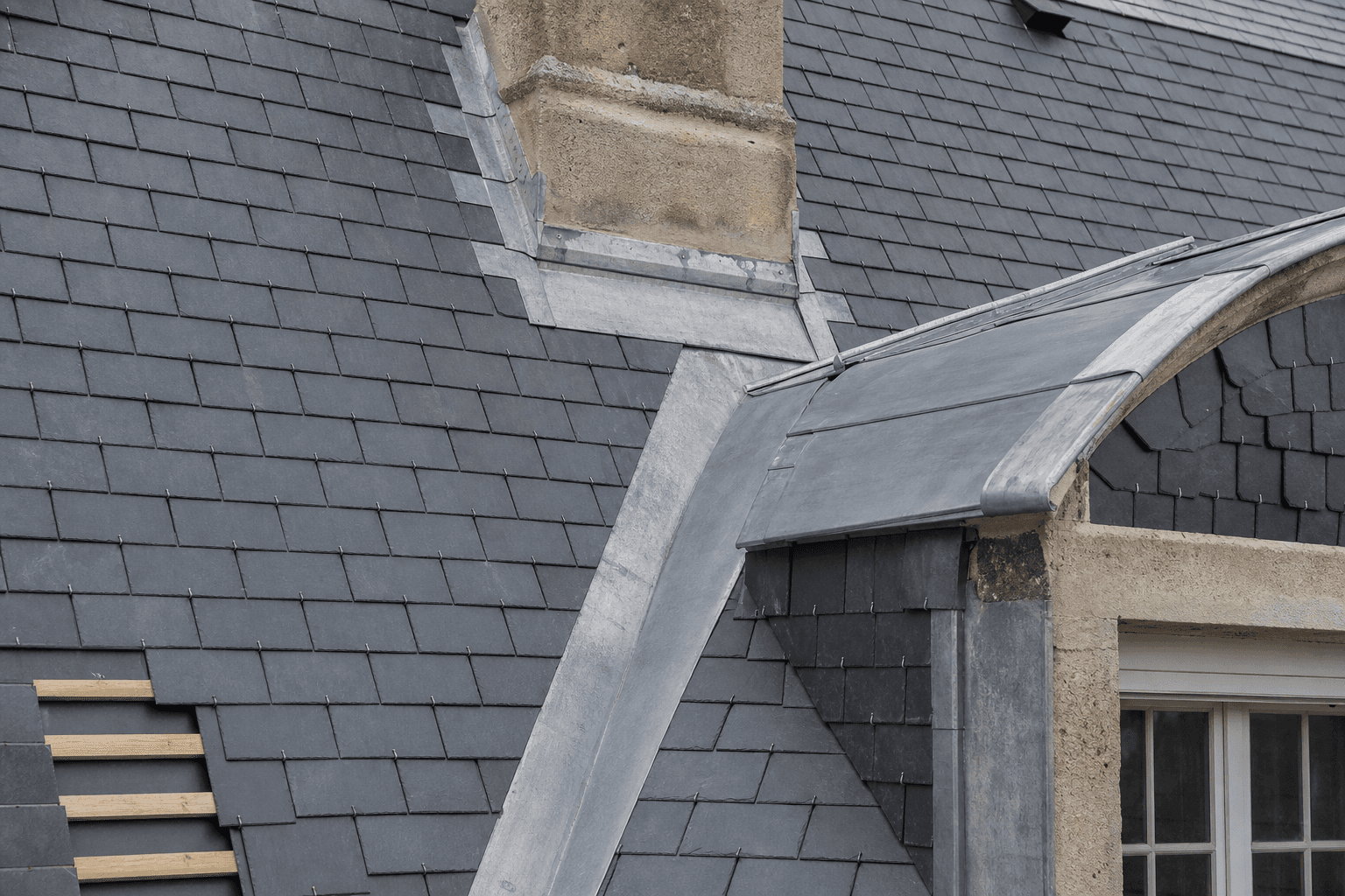 Détail d'ardoises naturelles posées au crochet inox avec noue et solin zinc façonnés sur mesure